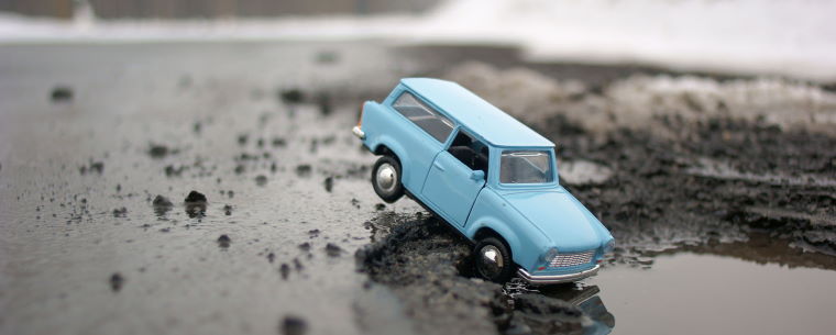 Small toy car in a large pothole